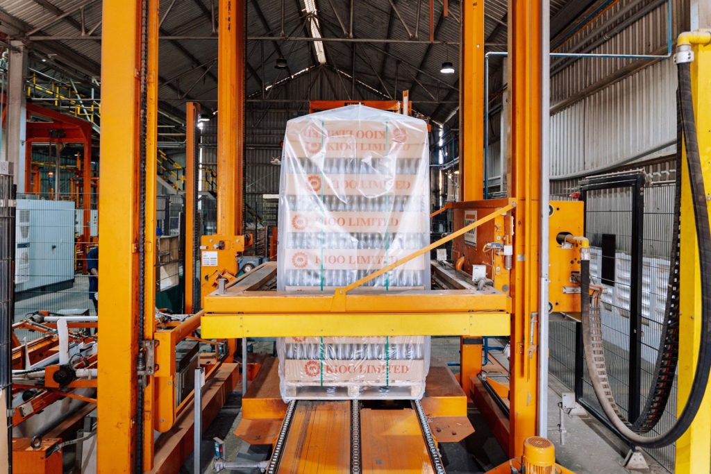 Une machine industrielle dans une verrerie de Dar es Salaam, illustrant un processus d'emballage automatisé.